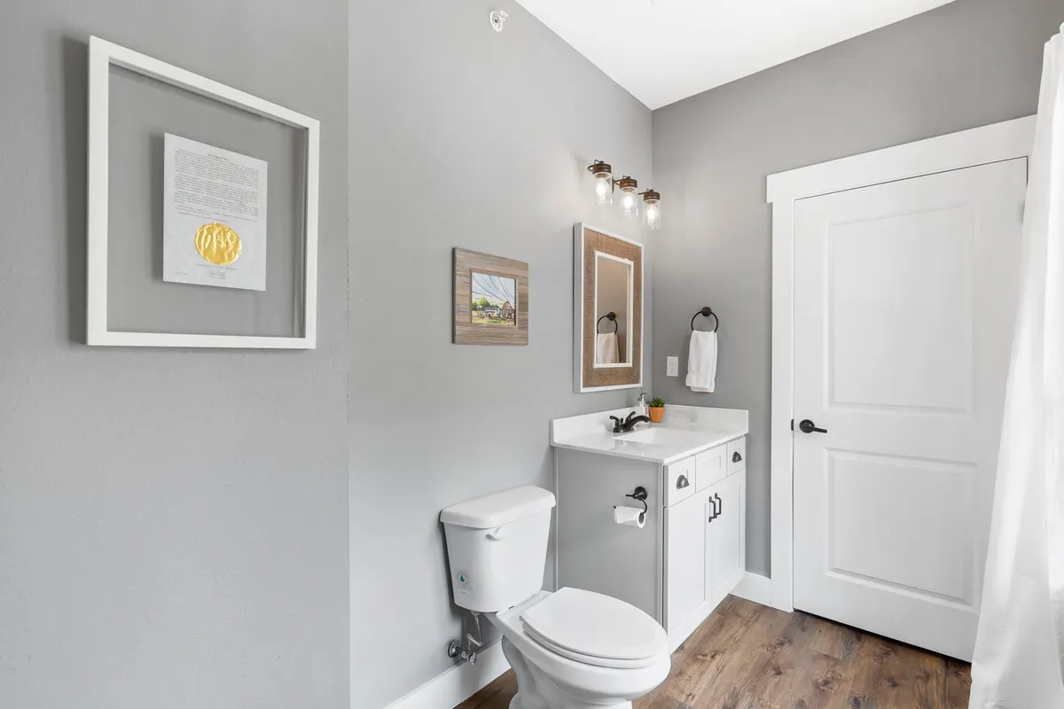 A modern bathroom with a stylish vanity, framed artwork, soft lighting, and a large mirror that creates a serene atmosphere. The space feels inviting and spa-like, aligning with the section's description of ensuite and spa-inspired bathrooms.